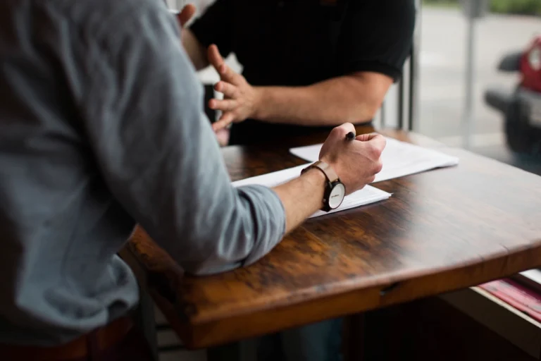 Two people reviewing paperwork across a table while discussing an asset appraisal