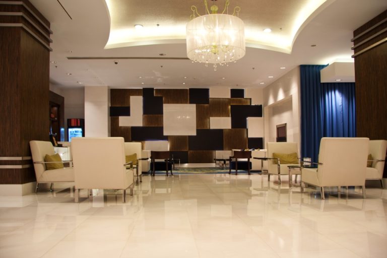 Hotel lobby seating area with grouped armchairs, low tables and recessed lighting